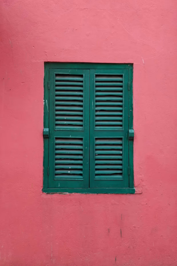 Ein dunkelgrünes Fenster in einer roten Wand