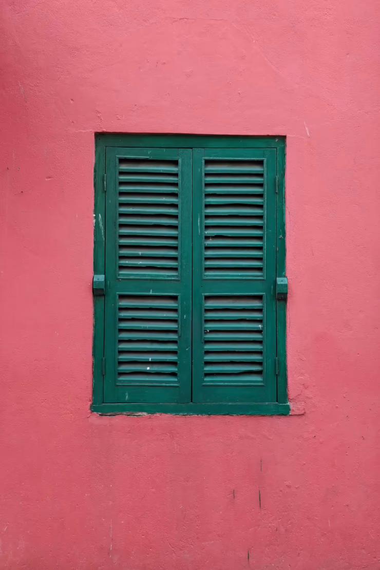 Ein dunkelgrünes Fenster in einer roten Wand