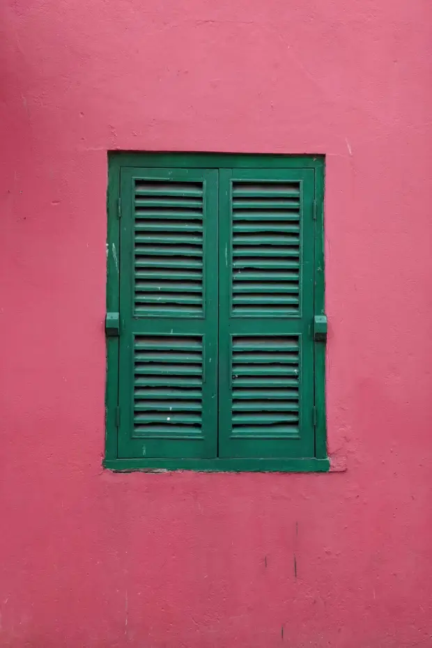 Ein dunkelgrünes Fenster in einer roten Wand