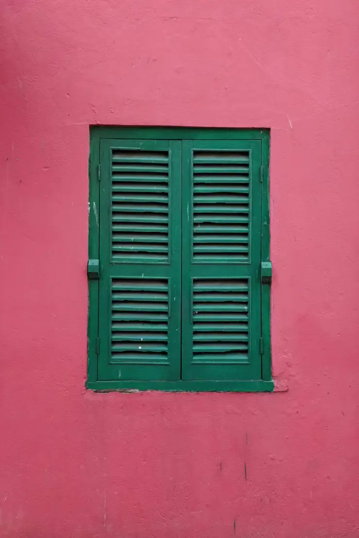 Ein dunkelgrünes Fenster in einer roten Wand